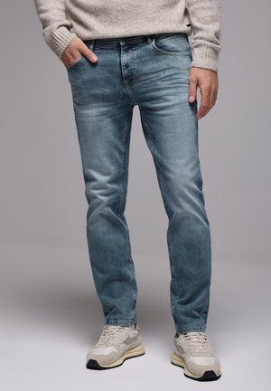 Lysblå denimjeans med en afslappet pasform, der har subtil falmen og fem-lomme-design, parret med cremefarvede sneakers.