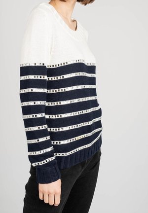 Pull en tricot avec des rayures horizontales bleu marine et blanches, agrémenté d'accents métalliques. Encolure et poignets côtelés. Coupe décontractée et tissu texturé.