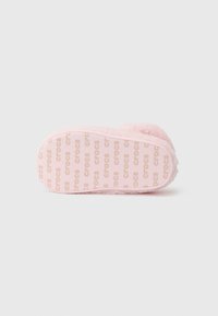 Rosa gefütterte Hausschuhe mit einer strukturierten Sohle, die das wiederholte "crocs"-Branding zeigt. Rundliche Form und weiches, flauschiges Material.