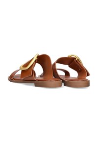 Sandalias de cuero marrón con suelas planas, que presentan un gran acento de hebilla dorada y un diseño de espalda abierta. Textura suave y estilo minimalista.