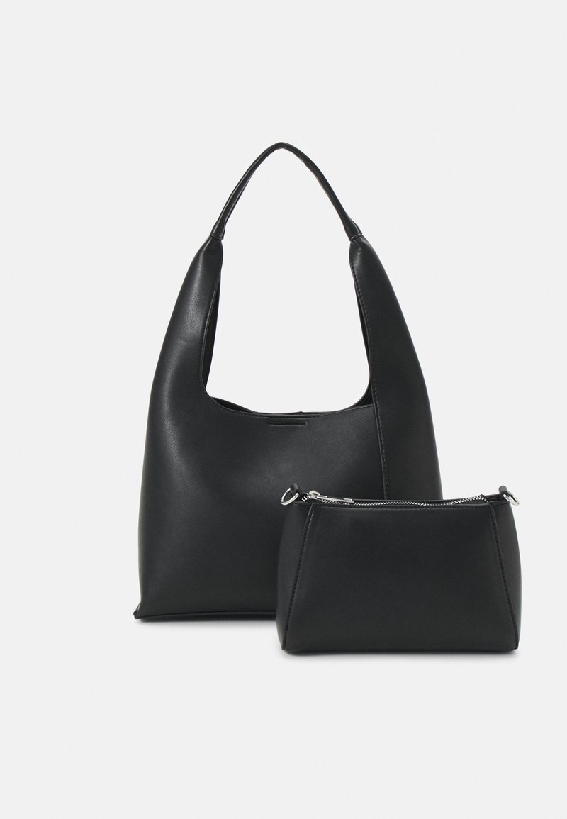 Sac à main en cuir noir avec une large anse et une petite pochette assortie à fermeture éclair, sur un fond uni.