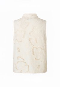 Haut blanc sans manches avec col montant, présentant une broderie florale et des motifs découpés sur tout le tissu.