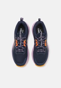 Mørkeblå joggesko med mesh-overside, lilla såle, oransje detaljer og mønstrede lisser. Utstyrt med en trekkflik på hælen for enkel påføring.