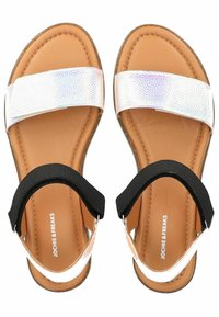 Platte sandalen met een tan kleurige binnenzool en zwarte elastische riemen, met een glanzende iriserende band over de wreef.