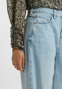 Jasnoniebieskie dżinsy o luźnym fasonie. Materiał ma zużytą teksturę, posiada przednie kieszenie oraz delikatne wyblakłe wykończenie.