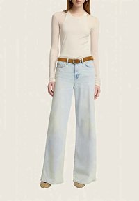 Un haut beige clair à manches longues associé à un jean large bleu clair. Une ceinture marron avec une boucle en argent se trouve à la taille. Tissu respirant.