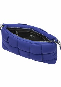 Niebieska torba na ramię z wyściółką, z teksturowanym pikowanym wzorem, srebrnymi okuciami i zamkiem błyskawicznym, odsłaniającym czarną podszewkę wewnętrzną.