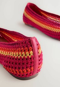 Virkkausbalettikengät, joissa on gradienttivärit vaaleanpunaisesta, oranssista ja keltaisesta. Pehmeä rakenne, jossa on kontrastina vaaleanpunainen nahkalenkki takana.