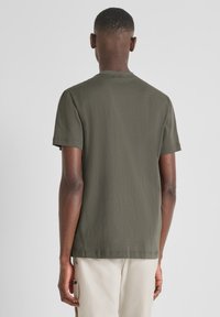 Camiseta de algodón verde oliva de manga corta, cuello redondo y corte relajado; textura suave, detalle de costura mínima en el dobladillo.