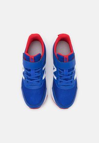 Blå träningsskor med röda accenter, nätöverdel, vit logotyp och en kardborreband. Har texturerad sula och vadderad krage för komfort.