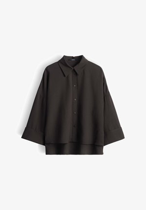 Camicia nera oversize con bottoni, polsini larghi e colletto classico, mostrata distesa su sfondo bianco.