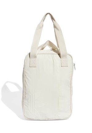 Sac fourre-tout rectangulaire beige avec deux larges anses, logo subtil embossé à l'avant et fermeture éclair en haut, projetant une ombre douce sur fond blanc.