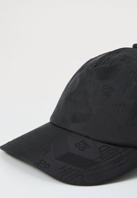 Schwarze Kappe mit einem sechseckigen Muster und geprägtem Branding. Gefertigt aus einem strukturierten Material mit einem gebogenen Schirm und verstellbarem Riemen.