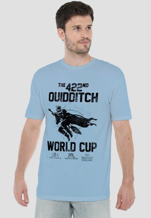 Man wearing light blue t-shirt with "422nd Quidditch World Cup" text and graphic of a flying figure holding a broomstick.