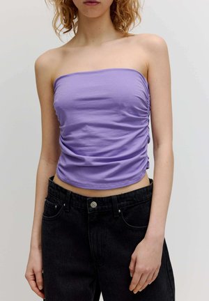Blausfarbener trägerloser Top aus glattem Stoff mit gerafften Seitendetails, kombiniert mit hochtaillierten schwarzen Jeans. Fokus auf Textur und Farbe.