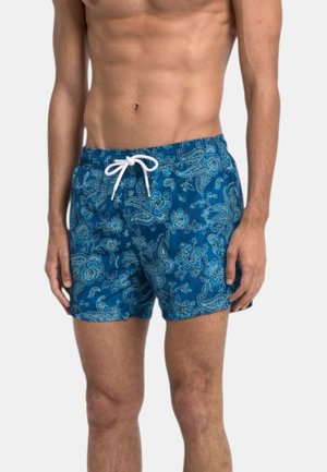 Torace maschile che indossa pantaloncini da bagno blu con motivo paisley e floreale bianco e coulisse bianca.