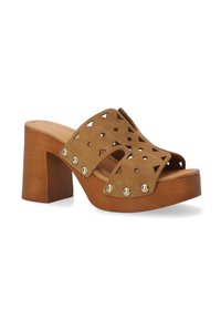 Leren platform mules in lichtbruin met uitgesneden geometrische patronen en gouden studaccenten. Houten blokhak voegt hoogte toe.