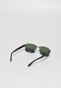 Ochelari de soare dreptunghiulari negri, cu lentile verzi, design elegant și brațe subțiri cu accente metalice și tampoane de cauciuc pentru nas.