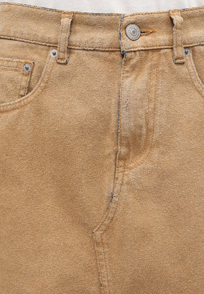 Παντελόνι από γνήσιο καστόρι σε ταμπά χρώμα με ορατές ραφές, θηλιές για ζώνη, μεταλλικό κουμπί κλεισίματος και εμπρόσθιες τσέπες με μεταλλικά καρφιά.