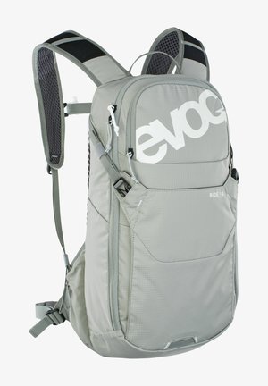 Light gray backpack with mesh shoulder straps, large logo, multiple zippered pockets, and durable fabric texture. Adjustable fit design.