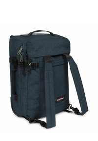 Reppu tummansinisestä kankaasta, suorakaiteen muotoinen, ylhäällä kahva, säädettävät hihnat, soljet ja logotieto sivussa. Karkea pinta.