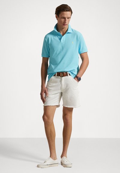 Polo de culoare albastru deschis cu guler, asortat cu pantaloni scurți din denim alb, cu marginile desfăcute. Purtați cu teniși albi și o curea maro.