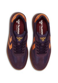 Ett par lila och orange Hummel-sneakers med meshtyg, mockadetaljer, snören och logotyp på tungan och innersulan, sett från ovan.