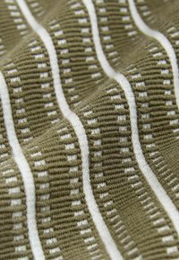 Olijfgroen stof met gestructureerde breipatronen. Witte horizontale strepen met kleine vierkanten creëren een contrasterend ontwerp doorheen.