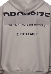 Sweat à capuche beige oversize avec texte noir "DROPSIZE", "WORK HARD, STAY HUMBLE" et "ELITE LEAGUE". Matière coton douce, design à capuche.