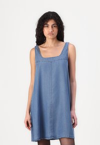 Denimmekjole med firkantet utringning, ermeløs design og avslappet passform. Lys blå farge med synlige sømmer og en jevn tekstur.