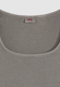 Tricou fără mâneci gri, din bumbac moale, cu o decolteu larg și cusături subțiri la margini. Eticheta este vizibilă în interiorul decolteului.