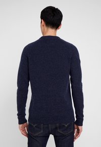 Maglione lavorato a maglia blu navy con collo a giro, caratterizzato da polsini e orlo a costine. Texture morbida, design aderente e senza motivi visibili.