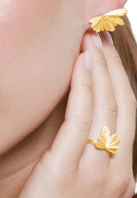 Set de bijoux dorés comprenant un ear cuff en forme de papillon et une bague. Fini texturé avec des ailes superposées, mettant en avant des détails de design complexes.