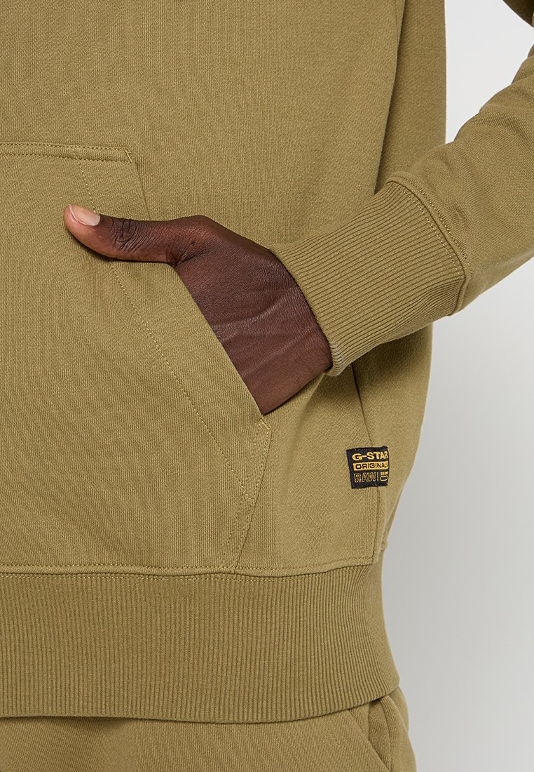 Olivgrüner Sweatshirt mit gerippten Bündchen und Saum, featuring einer Fronttasche und einem G-Star-Label, das auf der Tasche gestickt ist. Weicher, texturierter Stoff.