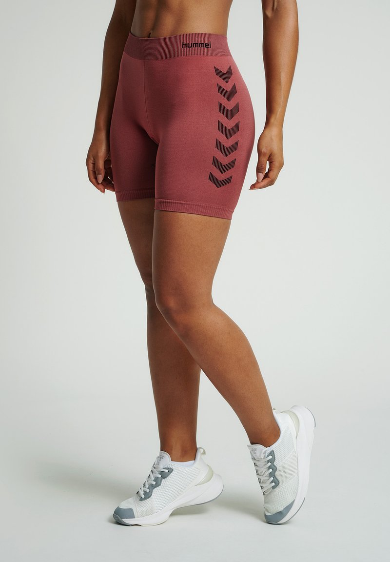 Maroon athletic shorts with a high waistband, featuring a black chevron pattern on the side. Paired with gray and white sneakers.