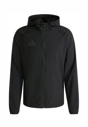 Chaqueta ligera negra con cremallera frontal, capucha ajustable y paneles laterales. Presenta un logo sutil en el pecho y puños elásticos.