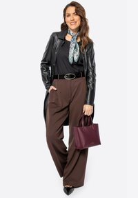 Chaqueta de cuero negra, top negro sin mangas, pantalones beige de pierna ancha, bufanda azul con flores, bolsa color burdeos y zapatos planos negros de punta. Texturas suaves y colores variados.