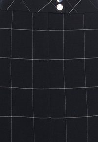 Jupe bleu marine à motif en grille, avec des lignes blanches, taille haute et boutons en métal argenté à l'avant. Confectionnée dans un tissu texturé.