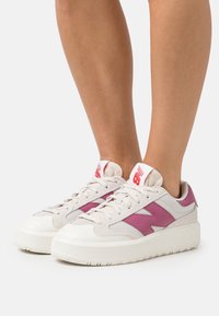 Zapatillas para hombre con parte superior de malla y ante en color beige, detalles en rosa y una suela plataforma blanca. Presenta un logo en la lengüeta.