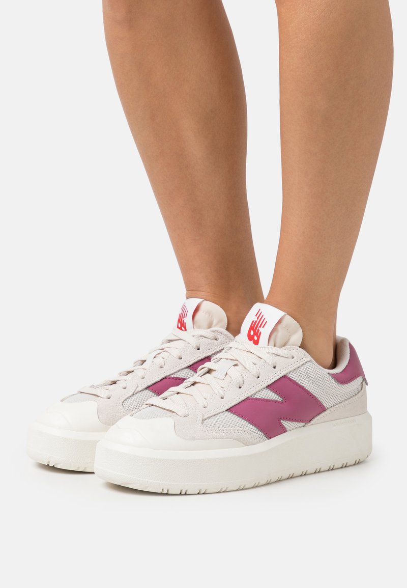 Zapatillas para hombre con parte superior de malla y ante en color beige, detalles en rosa y una suela plataforma blanca. Presenta un logo en la lengüeta.
