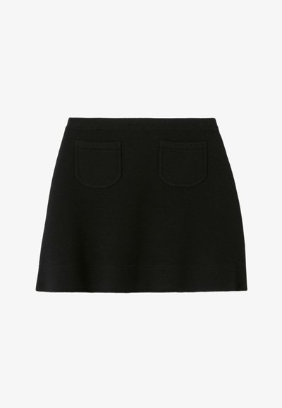 Jupe mini en maille noire avec une taille ajustée, deux poches arrière et une silhouette évasée. Texture lisse avec des lignes épurées.