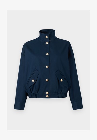 Σκούρο μπλε μπουφάν με ψηλό γιακά, χρυστά κουμπιά με κλιπ στο μπροστινό μέρος, ελαστική ρίγα στη μέση, και δύο μπροστινές τσέπες με καπάκι και κλείσιμο με χρυστά κουμπιά.