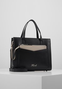 Hnědá strukturovaná kožená kabelka v černé barvě s béžovým akcentem. Obsahuje horní ucha, odnímatelný ramenní popruh a přední zipovou kapsu.