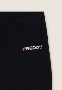 Leggings neri con una texture liscia, caratterizzati da un logo "FREDDY" in rosa oro metallizzato all'ormai. Tessuto elasticizzato per comfort e vestibilità.