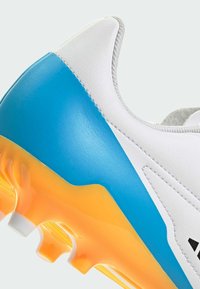 Fodboldsko med en hvid overdel, blå gradient-accenter og en orange-gul ydersål. Har tekstureret materiale og støbte studs.