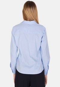 Camicia a maniche lunghe azzurro chiaro, design aderente, tessuto morbido in misto cotone, colletto classico, polsini abbottonati, texture liscia, orlo curvo.