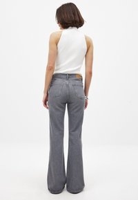 Harmaat leveälahkeiset farkut, jotka on valmistettu denimistä. Niissä on korkea vyötärö, viisi taskua ja nahkainen merkki takavyötäreellä.