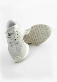 Jasnoszare sneakersy z siateczkową cholewką, zamszowymi akcentami, o zaokrąglonym nosku i gumowej podeszwie z teksturowanym wzorem bieżnika.