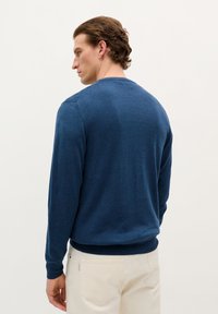 Maglione blu navy con scollo rotondo e maniche lunghe, realizzato in materiale morbido. Presenta polsini e orlo a coste. Texture liscia.