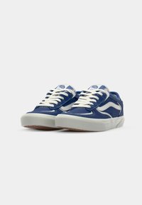 Blue canvas sneakers with white laces and accents; padded collar and perforated sides; rubber sole with textured grip pattern.